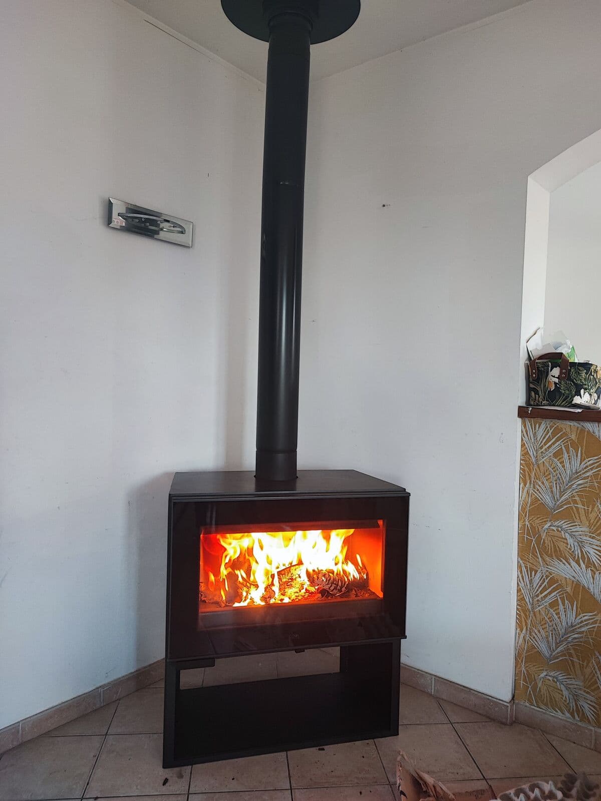 Installation d’un poêle à bois Denia modèle Finland à Morières-lès-Avignon, avec évacuation en plafond et large vitre horizontale laissant apparaître les flammes vives. Pose réalisée par Flamme Concept.